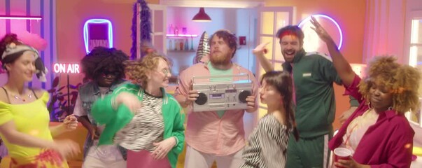 Company of multiethnic friends in bright trendy outfits dancing together at 90s disco party in room with colorful neon light