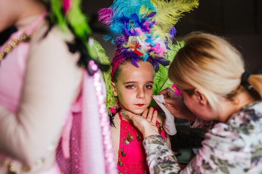 Anonymous mother applying festival makeup on daughter
