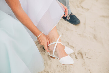 Marry at the North Sea. Bridal shoes on the beach. Bride takes off her shoes on the beach.