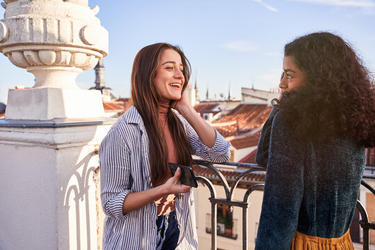 Cheerful diverse women chatting happily on rooftop