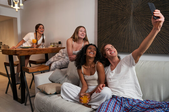 Joyful diverse flatmates taking selfie in living room