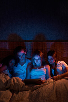 Scared flatmates watching horrors in dark bedroom