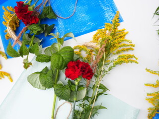 bright floral bouquets in wrappers lie on the table. Preparations flowers and materials for making ekiban bouquet composition by hands at master class. Roses and various herbs in festive package 