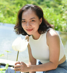 Vietnamese young woman smiling and smelling white lotus in Vietnam