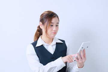 難しい顔をして計算機をはじく若いOL