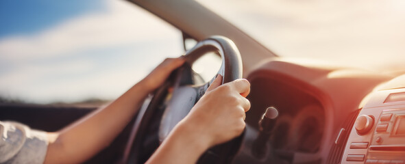 Woman's hands holding steering wheel inside car