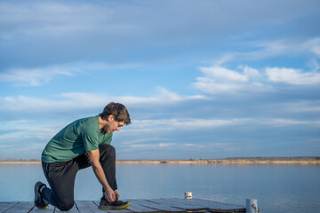Naklejka premium young boy tying his shoelaces against a blue sky