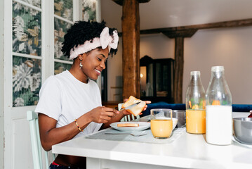 Black girl digging butter on a toast at breakfast