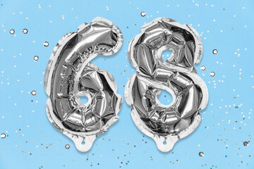 Silver foil balloon number, digit sixty eight on a blue background with sequins. Birthday greeting card with inscription 68. Top view. Numerical digit. Celebration event, template.