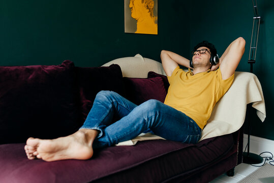 Attractive caucasian man lying on the couch listening music on h