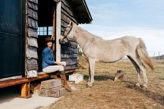 Woman with horses on porch of house