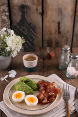Breakfast with bacon, eggs and coffee on a wooden table