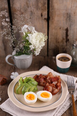 Breakfast with bacon, eggs and coffee on a wooden table