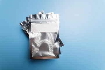 Silver plastic package body with transparent braces inside on a blue background. Invisible removable retainers for orthodontic treatment