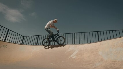 Urban extreme sport BMX. A man performs tricks in a skate park, on a ramp.