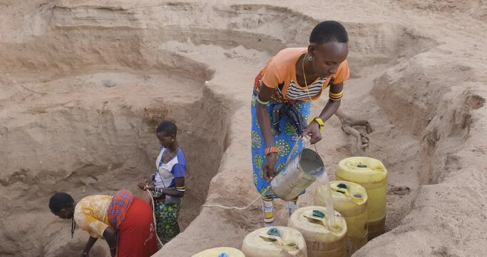 Climate change.drought.water crisis.Close-up.African woman collecting water in plastic containers from very deep wells due to persistent drought. Kenya