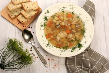 Fresh fish soup with vegetables in bowl on a white board background. Home kitchen recipes