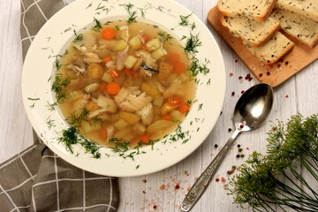 Fresh fish soup with vegetables in bowl on a white board background. Home kitchen recipes