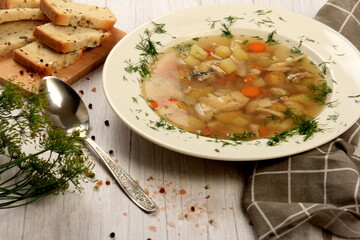 Fresh fish soup with vegetables in bowl on a white board background. Home kitchen recipes