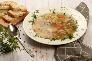Fresh fish soup with vegetables in bowl on a white board background. Home kitchen recipes