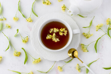Tea with linden in a white cup on a white marble table. White teapot with aromatic tea. Top view