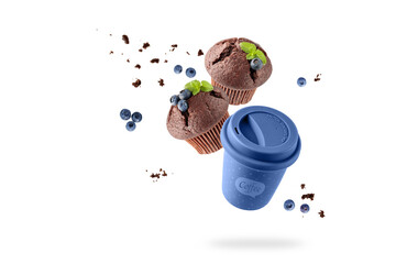 Blue to go cup hot coffee and two chocolate muffins with blueberry berries and crumbs flying...