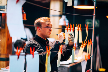 Man hanging papers with orders on kitchen