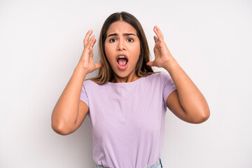 hispanic latin pretty woman screaming with hands up in the air, feeling furious, frustrated,...