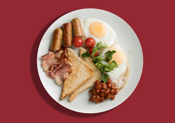 A plate with scrambled eggs, bacon, beans, sausages, tomatoes and croutons on a red background.