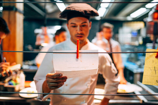 Man reading orders on paper working in kitchen
