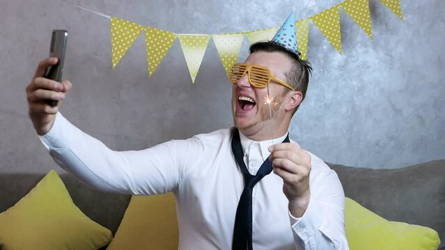 Smiling man celebrates his birthday. A very happy young man celebrates his birthday, a man with begal lights in his hands, holiday garlands