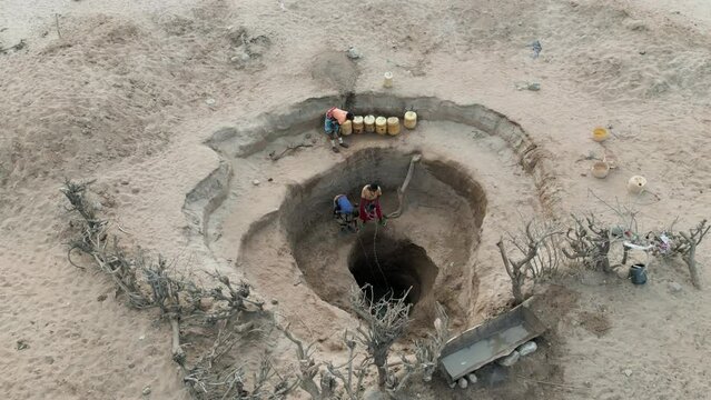 Climate change.drought.water crisis.Straight down aerial view.African woman collecting water in plastic containers from very deep wells due to persistent drought. Kenya