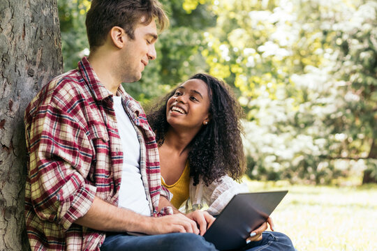 Happy Diverse Couple Using Laptop In Park