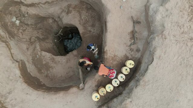 Climate change.drought.water crisis.Straight down aerial view.African woman collecting water in plastic containers from very deep wells due to persistent drought. Kenya