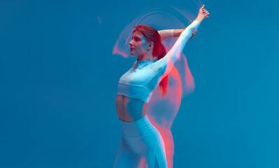 Fitness model slim girl raised hand, stretching back. Pilates workout. Long exposure, colorful neon...