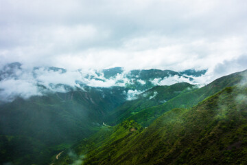 Hills in the Himalayas with green trees covered in mist and white clouds after a rainfall. Uttarakhand India.