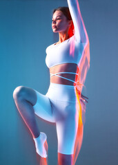 Female athlete exercising, young girl training on blue backdrop. Fitness, aerobics workout. Motion...