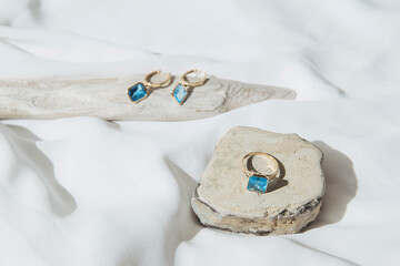 Elegant jewellery set of gold earrings and ring with blue topaz on white background with stone and...