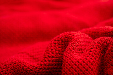 Knitted surface of woolen things as a background. Close-up of soft fabric red color knitted patterns texture. Warm winter clothing. Background textile surface with copy space for text.