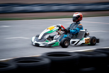 Go kart racing field, racer wearing safety uniform on competition tournament. 