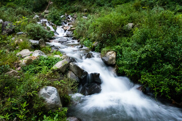 Fototapeta premium A wide angle shot of a river flowing through the forest with mountain surrounding in India. Dehradun city of uttarakhand.