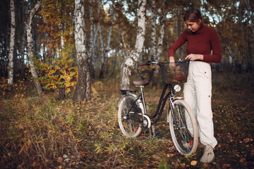 Fototapeta na wymiar Happy active young woman riding bicycle in autumn park.