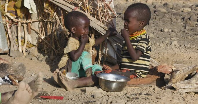 Close-up.Malnourished children due to extreme poverty, drought and climate change. Eating maize porridge infront of their dwelling.Kenya