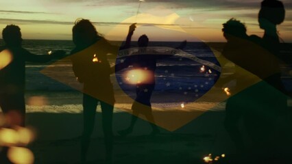 Composite video of waving brazil flag over group of friends with sparklers dancing at the beach - Powered by Adobe