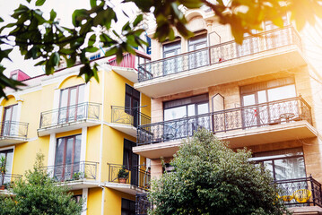 Fototapeta na wymiar The facade of house with beautiful balcony in summer sun rays. Balcony with metal railings. Laconic minimalist concept