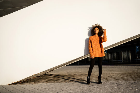 Trendy black woman in bright sweater on street