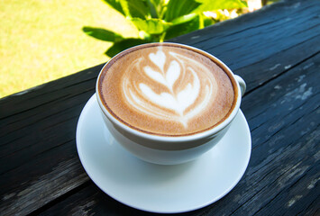Latte coffee cup on wooden floor in garden.