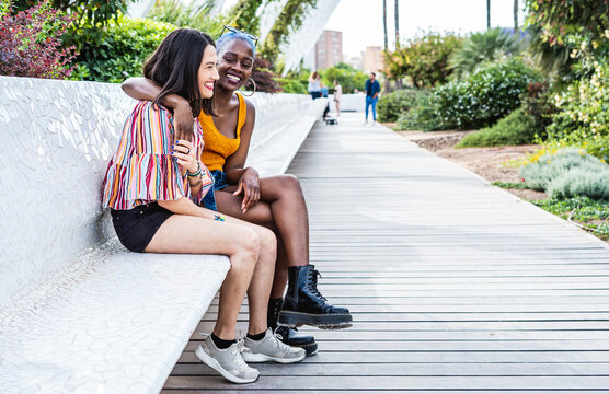 Multiracial lesbian couple hugging on bench