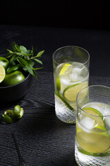 Dos vasos de refrescante zumo de lima con rodajas de lima y hielo sobre fondo negro