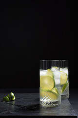 Dos vasos de refrescante zumo de lima con rodajas de lima y hielo sobre fondo negro